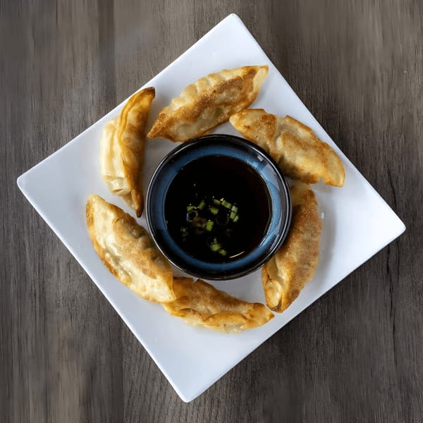 Zake Sushi & Ramen's fried gyoza arranged around a bowl of soy sauce with scallions.